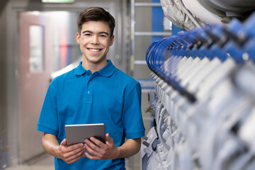 Happy technician holding tablet PC standing at factory