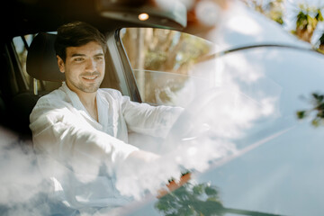 Smiling man using conrol panel in electric car seen through windshield