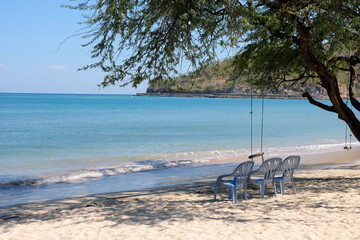 A tree swing and a row of empty chairs on the beach with stunning blue ocean in Dili, Timor Leste