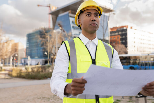 Engineer holding blueprint working at construction site