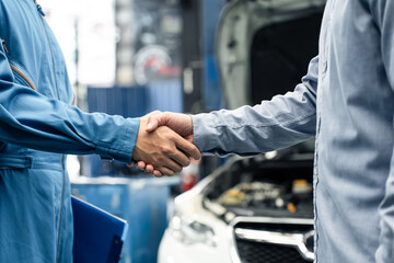 Asian automotive mechanic repairman handshake with client in garage. - obrazy, fototapety, plakaty