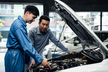 Fototapeta na wymiar Asian automotive mechanic explain car condition to client in garage. 