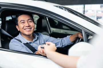 Asian automotive mechanic repairman handing car remote key to client. 
