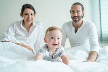 Fototapeta premium Portrait of Caucasian happy family smiling, look at camera in bedroom. 