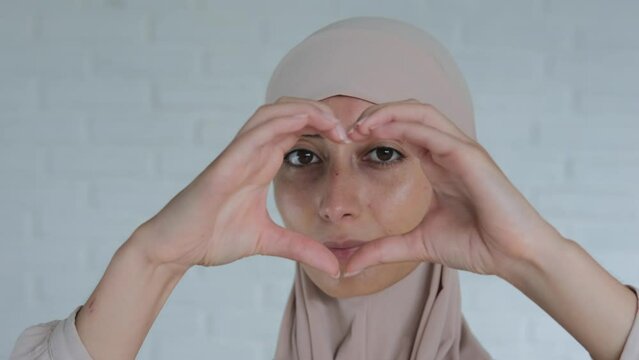 Nice woman in hijab showing heart sign with hands, Gesture of love from muslim world to all humanity. Sign of world peace from a woman of the Islamic faith in the Arab world.