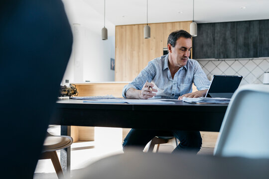 Musician e-learning through tablet PC sitting in kitchen at table