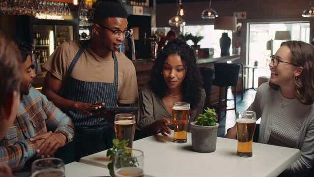 African American waiter taking orders from customers on digital tablet
