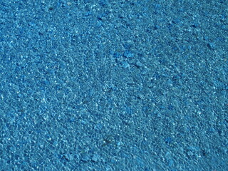 大雨でできた風に吹かれる石ころ道の水溜まりの水面の模様