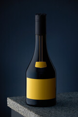 A bottle of expensive alcohol, whiskey, cognac, brandy with a yellow label on a marble surface and a dark blue background.