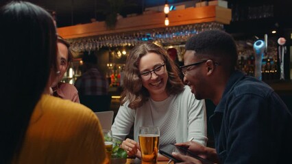 Diverse group of work colleagues out for drinks chatting and laughing