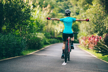 Woman feel free cycling on tropical park trail in summer