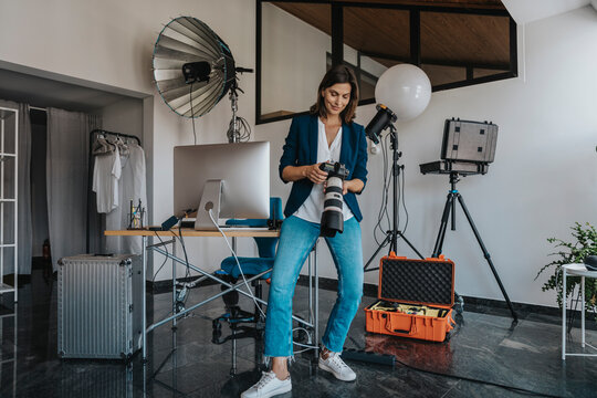 Photographer holding camera standing in studio