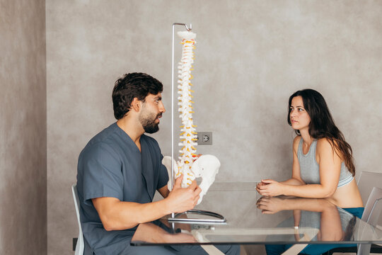 Physiotherapist explaining human spine anatomy to woman