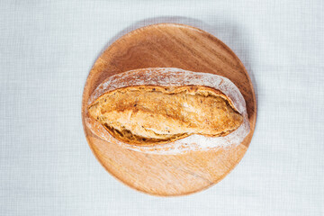 Loaf of sourdough bread on a bright background. Minimalist scene. Hands holding bread.