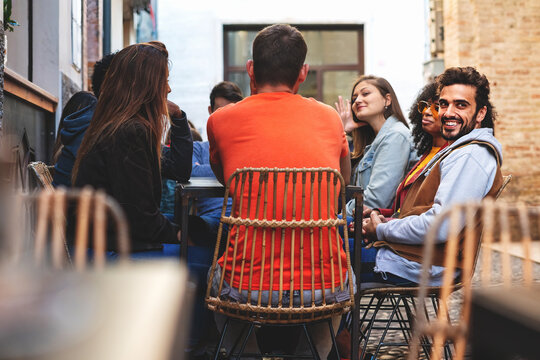 Fototapeta Group of young people sitting outdoors at cafe - friends having fun on weekend talking carefree at the street cafe