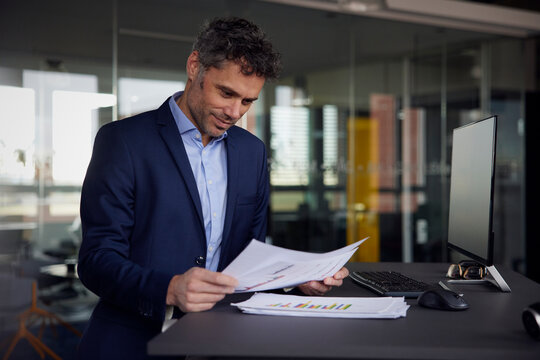 Businessman reading document standing at desk in office