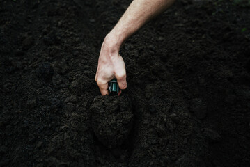 a man digs the soil with a shovel to plant flowers, greenery or herbs
