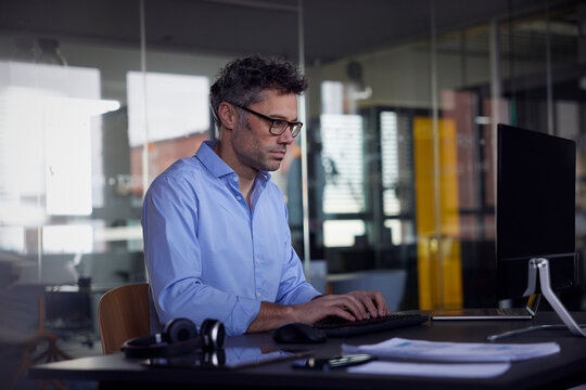 Businessman using desktop PC sitting at desk in office
