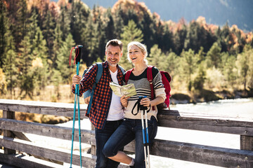 Austria, Alps, happy couple on a hiking trip with map on a bridge