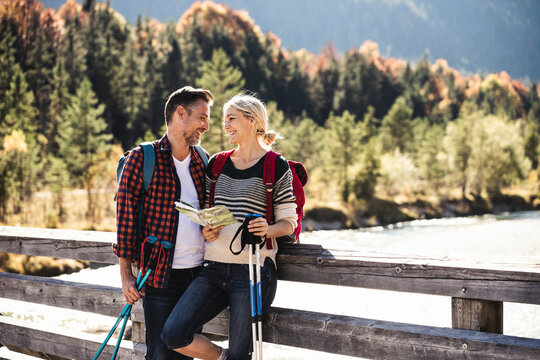Austria, Alps, happy couple on a hiking trip with map on a bridge