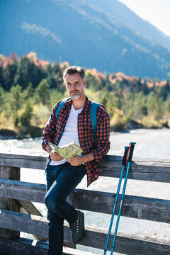 Austria, Alps, man on a hiking trip with map on a bridge