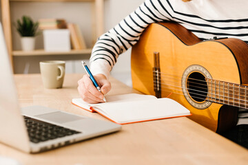 Man with guitar writing musical note sitting at table