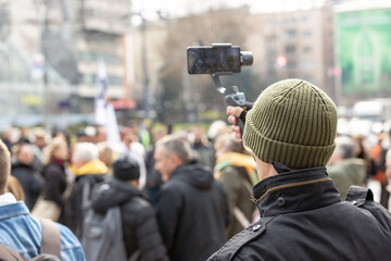Mobile journalist filming crowd of people with a smartphone