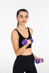 Young beautiful woman doing exercises with dumbbell in gym.