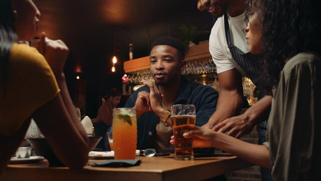 African American waiter placing bill collecting food from customers after celebratory dinner