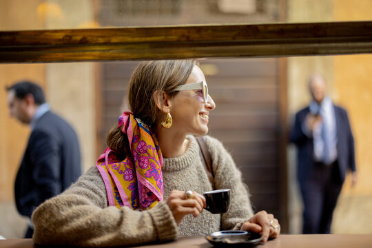 Fototapeta Woman drinking espresso coffee at traditional old style italian cafe on a bar at window on cozy street. Concept of italian lifestyle