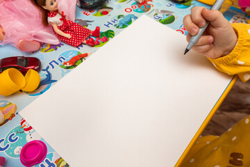 child sitting at a table with a blank sheet of paper