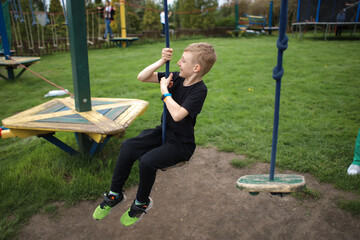 the boy goes through an obstacle course is engaged in active sports sits on a suspended swing