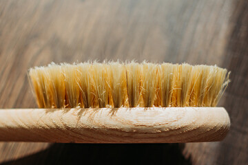 wooden massage brush with natural bristles on wooden background in sunlight. side view