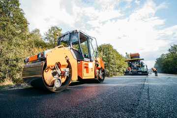 Fototapeta na wymiar Vibratory asphalt rollers compactor compacting new asphalt pavement. Road service repairs the highway