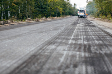 Road milling machine removes asphalt from old road and loads milled asphalt in dump truck.  - obrazy, fototapety, plakaty