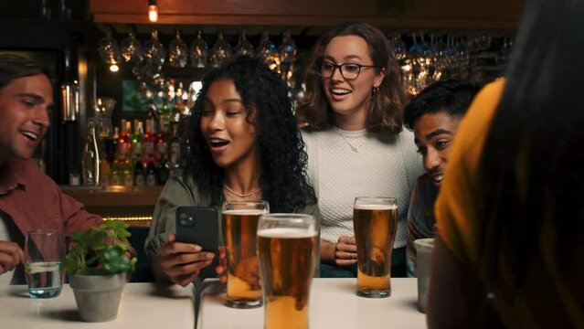 Diverse group of friends talking on video call in restaurant