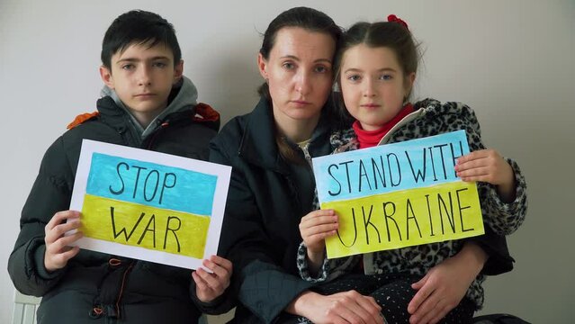 Family in refugee centre holding motivational packards with text Stop war and Stand with Ukraine against armored conflict. Crisis, peace, stop aggression in whole world