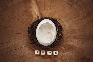 Chicken egg in a nest on a wood texture with the inscription love close-up