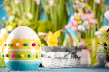 Easter time. Easter decorations on blue painted wooden table. Easter bunny, easter eggs in basket and cabbage leaf.