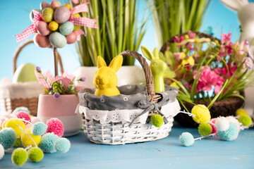 Easter time. Easter decorations on blue painted wooden table. Easter bunny, easter eggs in basket and cabbage leaf.