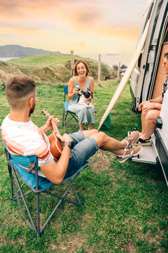 Group of friends with their dog drinking beer in front of their camper van