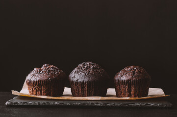 Chocolate muffin on dark background. Dark lighting. Homemade delicious chocolate muffins on black...