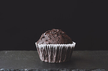 cupcake on stone board. Chocolate muffin on black background. Dark lighting