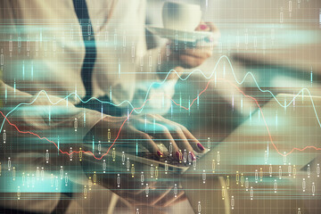 Double exposure of businesswoman hands typing on computer and financial graph hologram drawing. Stock market analysis concept.