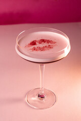 red festive cocktail with a flower on a pink background