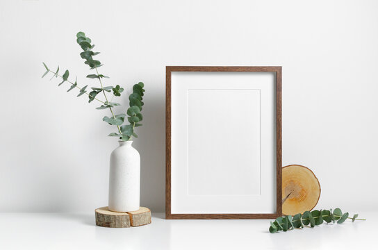 Vertical frame mockup in white minimalistic interior with flowers decorations.