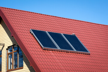 Solar energy. Water solar collector on a red metal roof