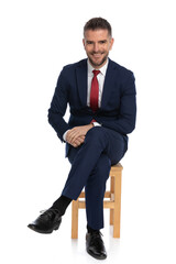 elegant man in his forties with beard crossing legs while sitting