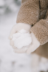 girl in gloves holding snow in her hands