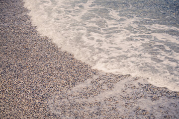 The beach of the Mediterranean coast with waves of azure water. Summer sea breeze. Selective focus